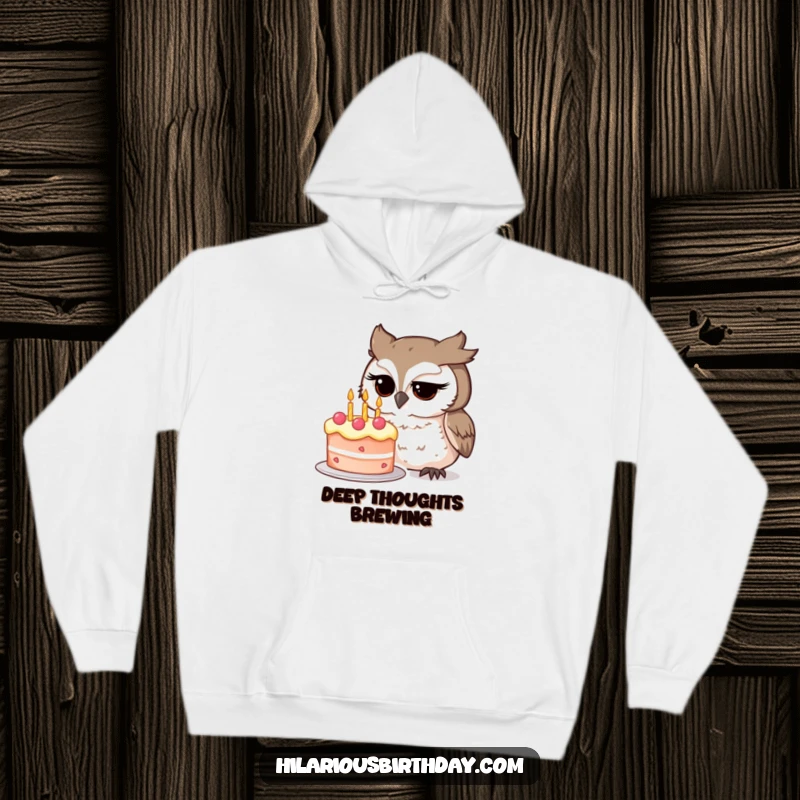 Funny owl character intently studying a whimsical birthday cake on this cozy hoodie, showcasing thoughtful curiosity, a superb funny gift.
