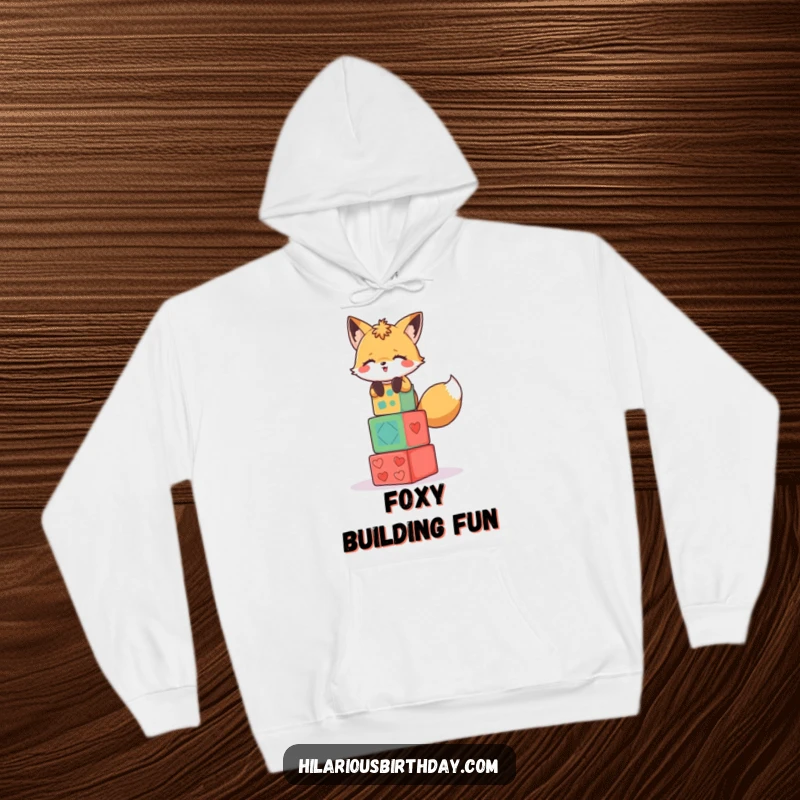 Funny hoodie featuring a giggling fox character precariously stacking colorful party blocks.