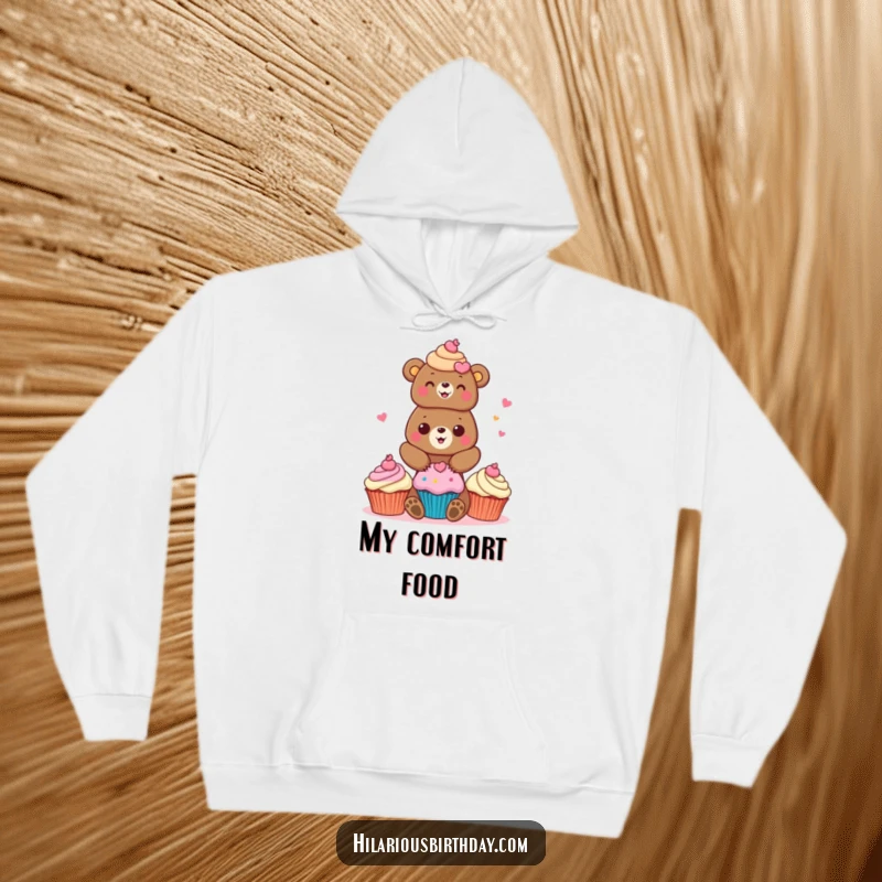 Funny bear hoodie showcasing a cheerful bear character stacking brightly colored cupcakes, perfect for cozy comfort.
