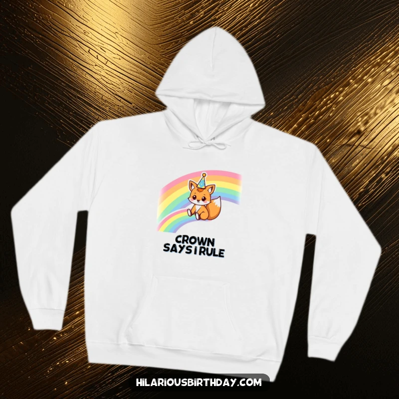Funny hoodie featuring a kawaii fox character sliding down a rainbow wearing a party crown, offering warmth and a dose of magical humor.