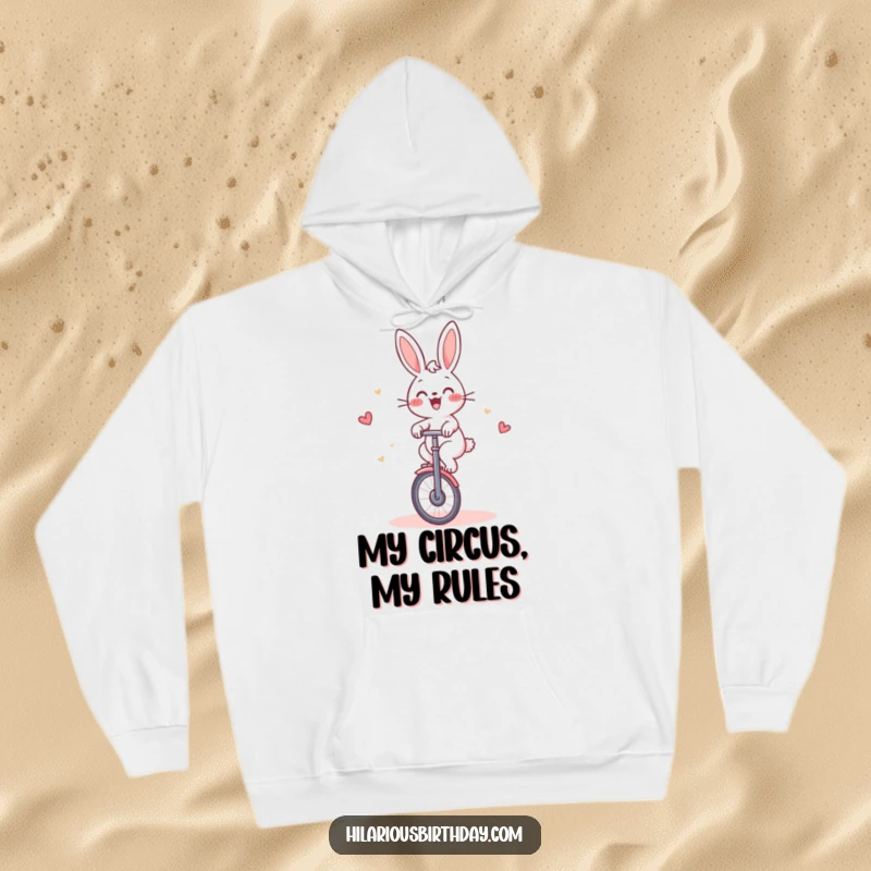 Funny Rabbit Hoodie: Cheerful rabbit gleefully riding a unicycle around a cake, ideal for cozy humor.