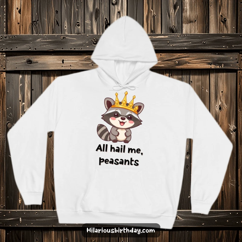 Funny hoodie showcasing a happy raccoon character triumphantly wearing a shiny golden crown, a symbol of power and humor.